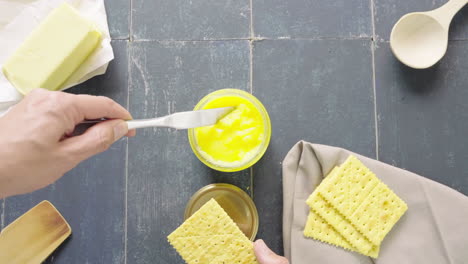 man's hand extracts butter ghee from a pot with a knife