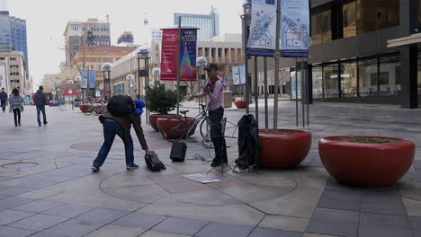 a guy giving money to a violinist in downtown denver colorado