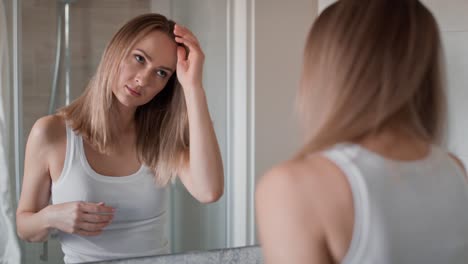 caucasian woman checking hair condition in the bathroom.