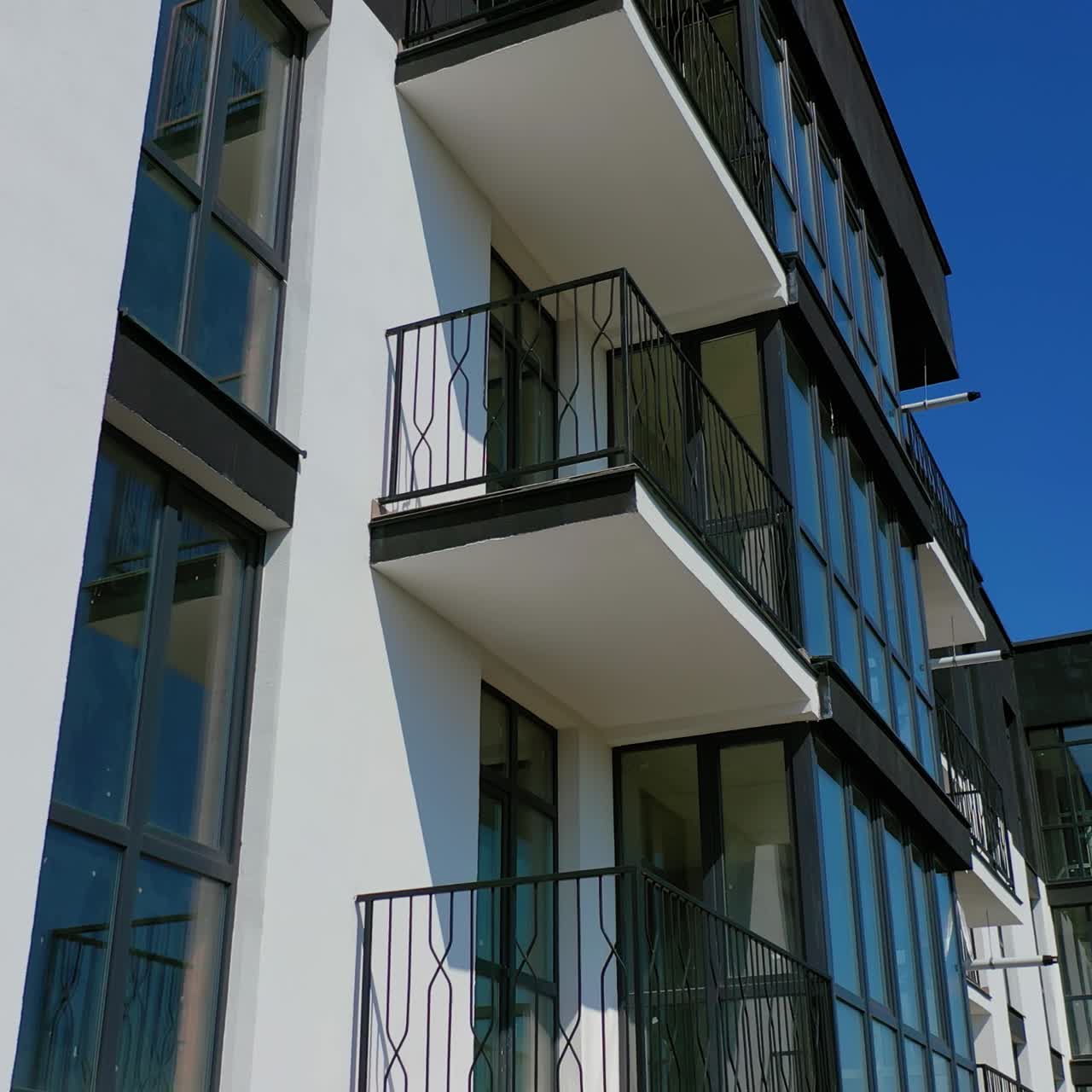 Tall black and white architecture. Modern facade of new residential building with balconies. Camera moves top down.