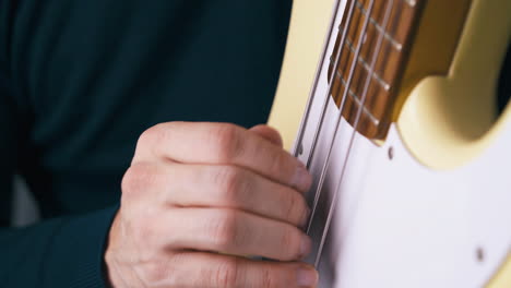 persona sostiene la guitarra bajo en posición vertical y toca