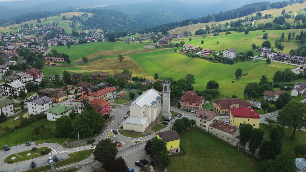 Treschè Conca village in Roana, church, houses, and green mountain landscape in Italian Alps, Italy. Aerial drone