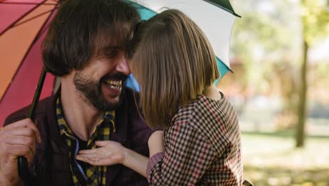 Handheld-view-of-father-and-daughter-under-colorful-umbrella