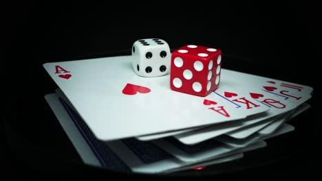 straight flush cards with red and white dice on top - rotating on a reflective surface, studio shot