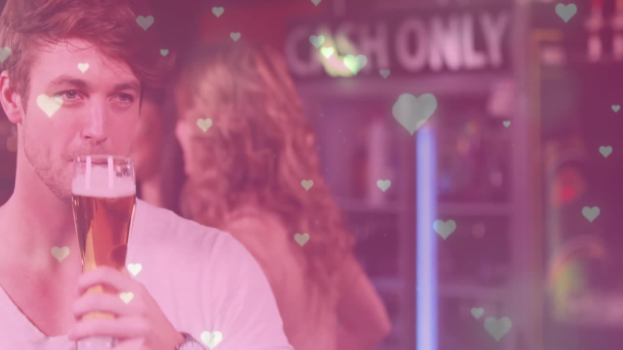 man sipping pint glass in dim bar, with heart-shaped bokeh overlays and neon sign for marketing