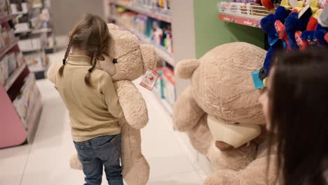 Mother-gives-big-soft-bear-toy-to-her-daughter-in-children's-department-store