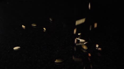 Kernel-dropping-in-slow-motion-on-a-black-surface,-isolated-in-black-background