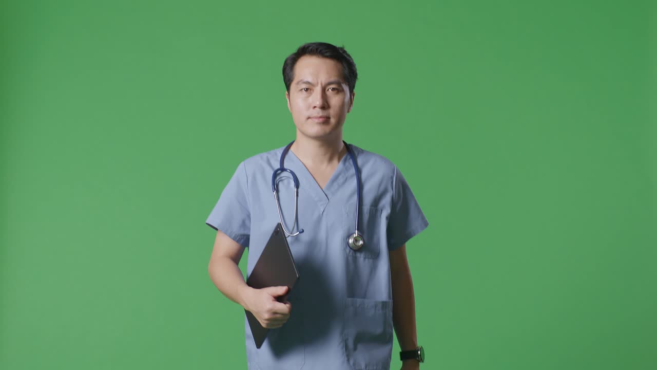 병원 에서 녹색 스크린 배경 에 걸어 다니는 동안 태블릿 을 들고 있는 스테토스코프 를 들고 있는 아시아 남자 의사