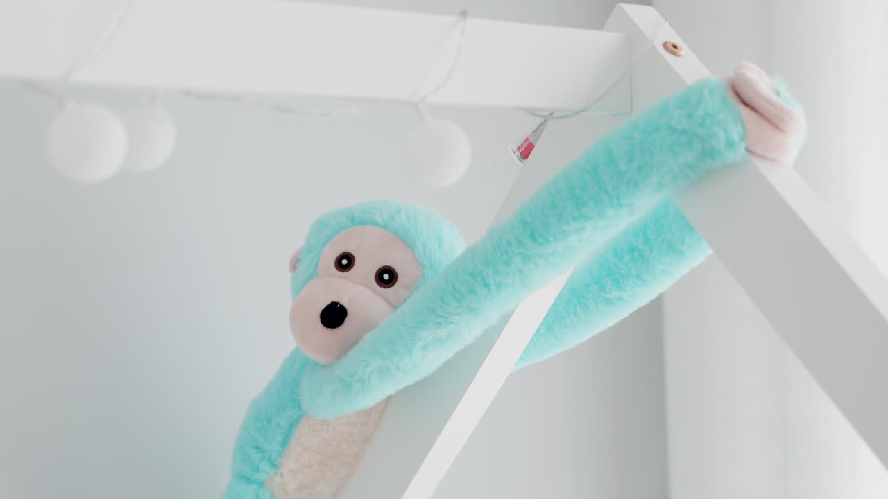 soft blue monkey plush hanging in bright white minimalist kids room