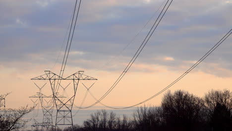 Lange-Herabstürzende-Elektrische-Übertragungsleitungen,-Die-Bei-Sonnenuntergang-Zu-Elektrischen-Pylonentürmen-Führen