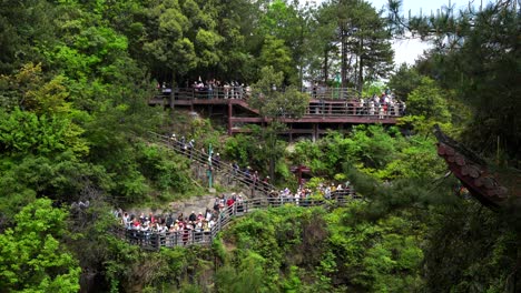 tourists exploring yuanjiajie scenic area in zhangjiajie on a lush cliffside walkway, china