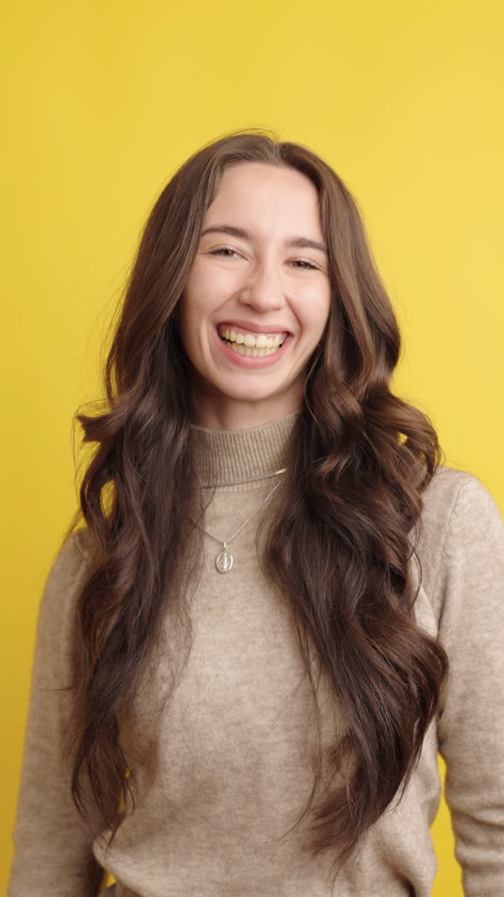 Cheerful woman smiling on yellow background in studio setting