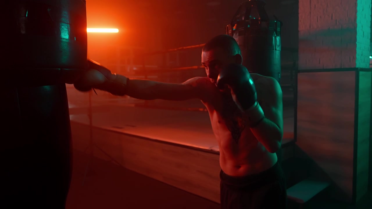 Pugile a torso nudo che si allena con il sacco da boxe in una palestra illuminata al neon