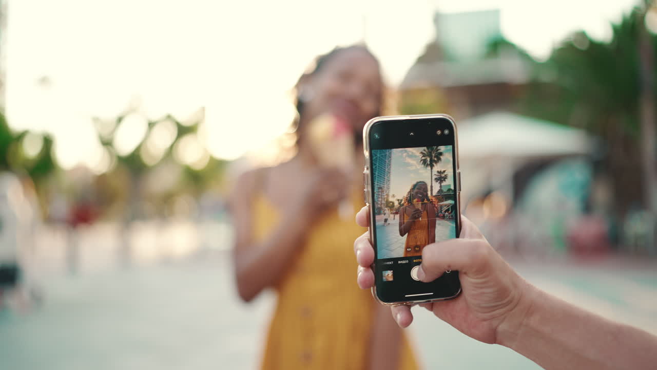 Donna che si fa un selfie con un gelato in una strada soleggiata