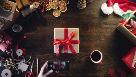 top view woman photographing christmas decorations drinking coffee christmas presents table from above - red epic dragon