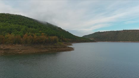 Aerial-view-along-shore-of-Embalse-de-Rialb,-Reservoir-with-calm-waters