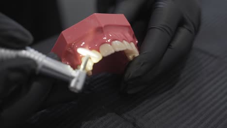 close up of gloved hands polishing a dental mold using a dental drill tool