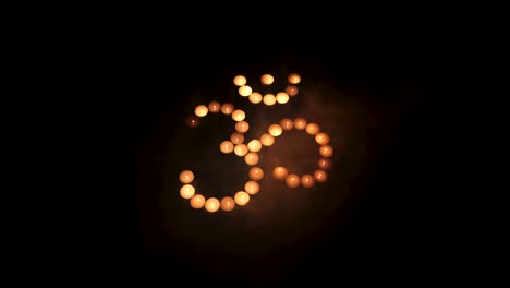 om symbol from burning candles with smoke movement on black background