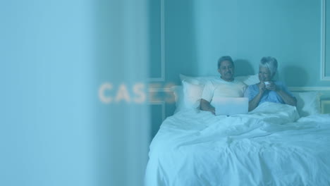 animation of covid 19 text over senior couple at home using laptop in bed