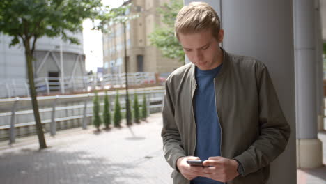 young white man messaging with smartphone in urban setting