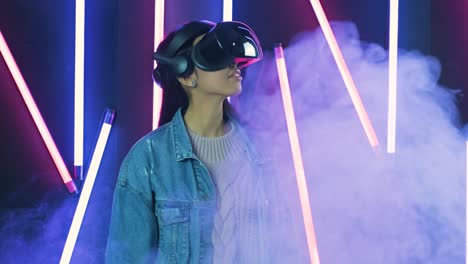 joven mira a su alrededor y se pregunta cómo increíble en la realidad virtual. casco de realidad virtual en color iluminación humo de fondo