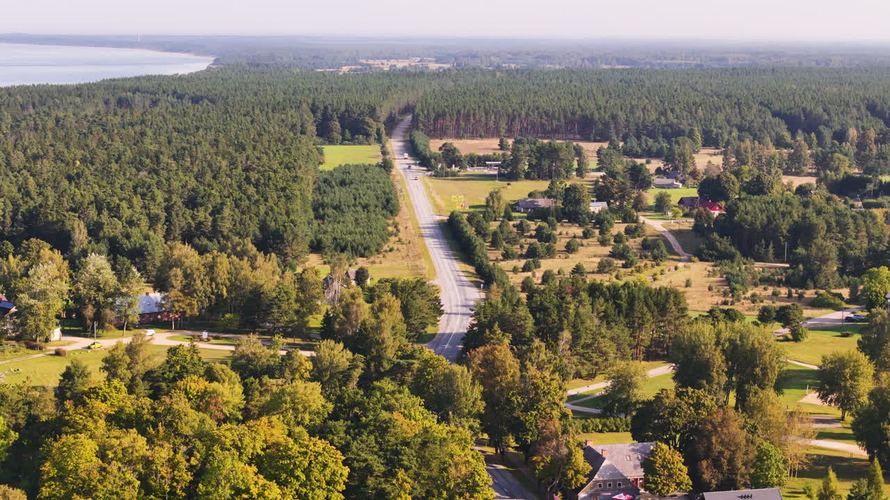 Road Through Lush Forested Landscape With Houses. Coastline Village Of Jurkalne In Latvia. aerial shot