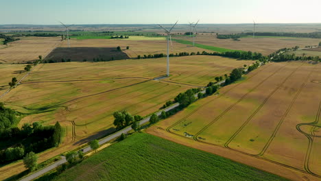 Aerial-view-of-wind-turbines-scattered-across-golden-wheat-fields,-highlighting-the-blend-of-agriculture-and-renewable-energy-in-the-rural-landscape