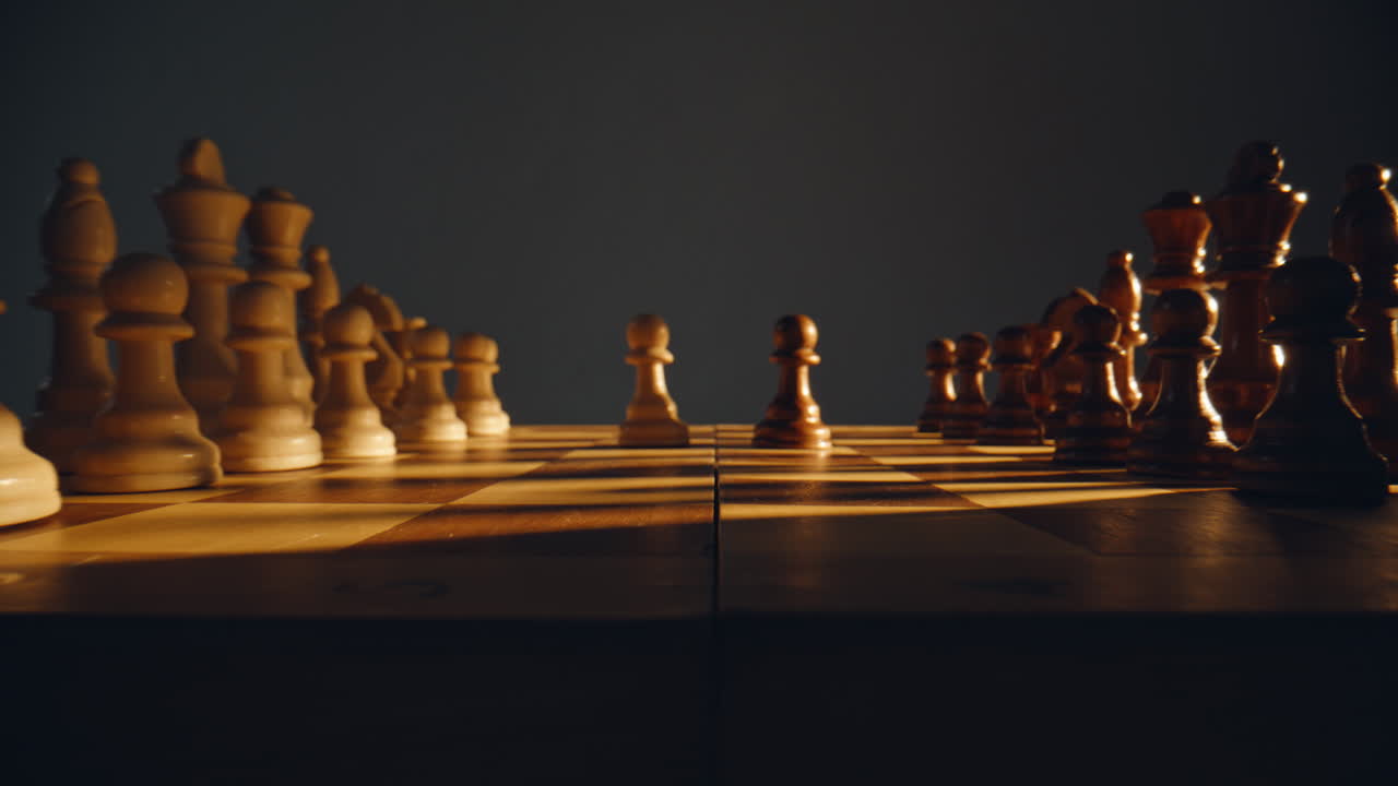 Two pawns standing chessboard closeup. Chess pieces on sunlight checkered board