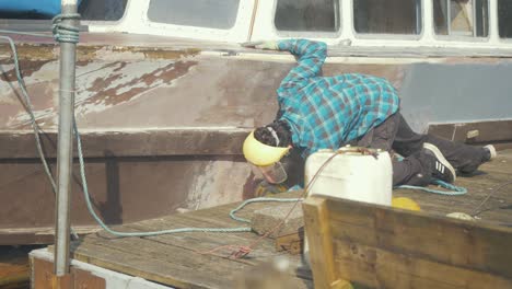 sanding hull of wooden motor cruiser