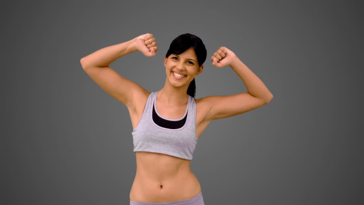 una morena en forma mostrando sus músculos del brazo.