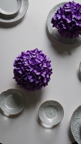 purple floral centerpiece with decorative plates on white table