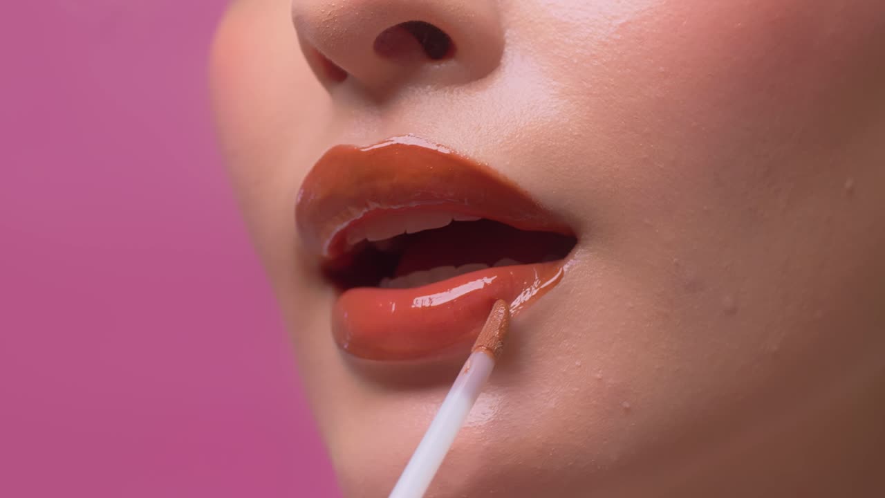 un primer plano de una mujer aplicando brillo labial en sus labios rojos sexy