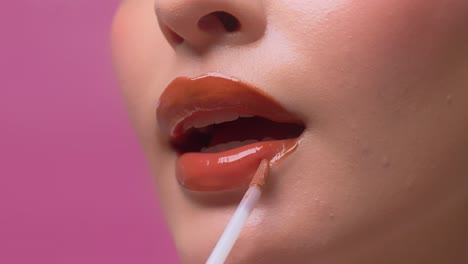 close up of woman applying lip gloss on her sexy red lips