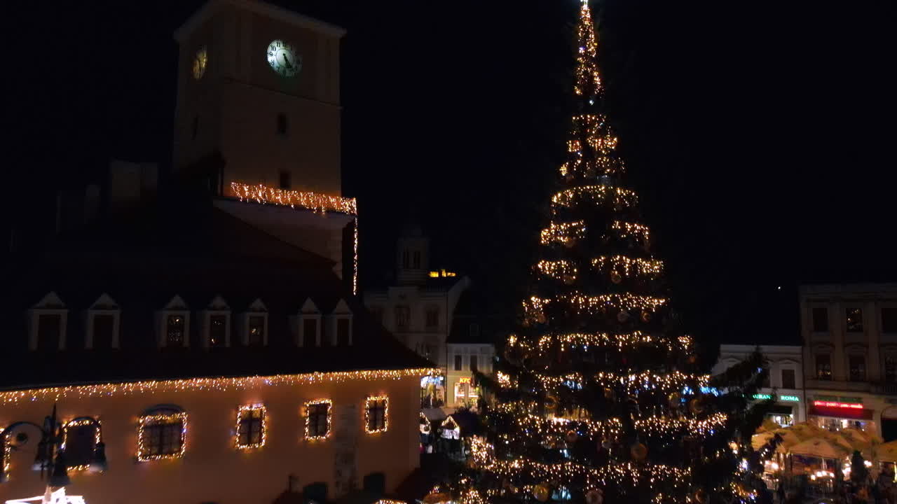 Aerial drone view of The Council Square at dusk in Brasov, Romania. Old city centre decorated for Christmas. County Museum of History, buildings, people