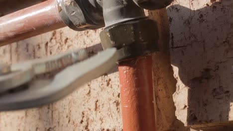 static shot of a leaking tap being fixed by a man