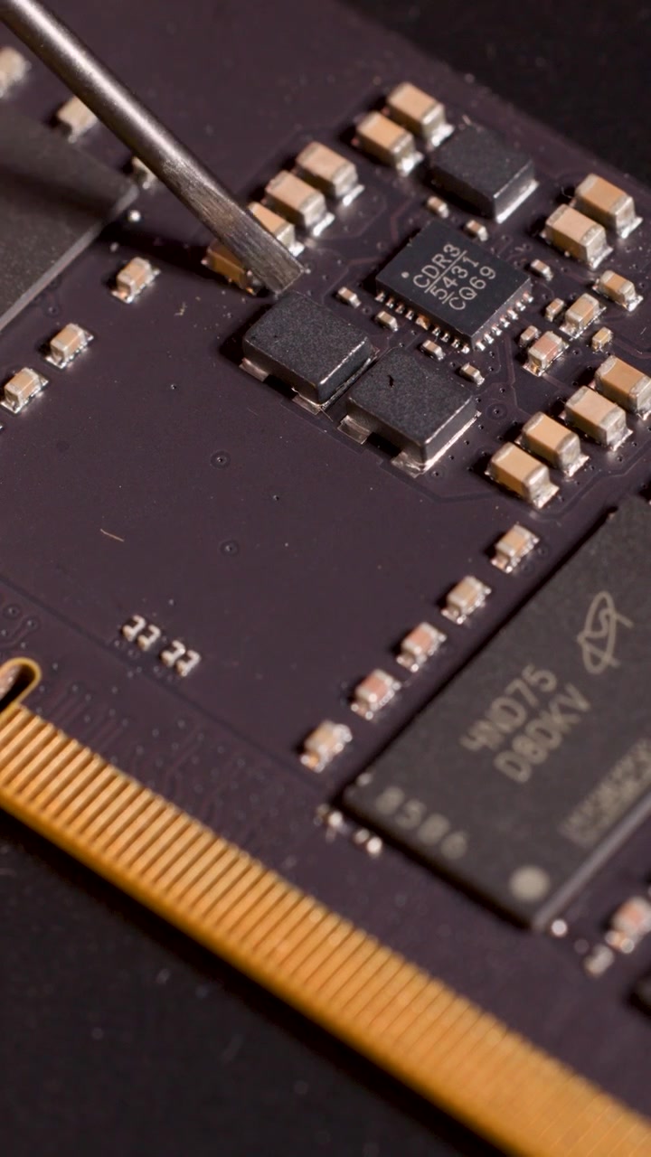Strumento metallico indica con precisione un microchip su un circuito stampato sotto un'illuminazione calda, vista macro ravvicinata