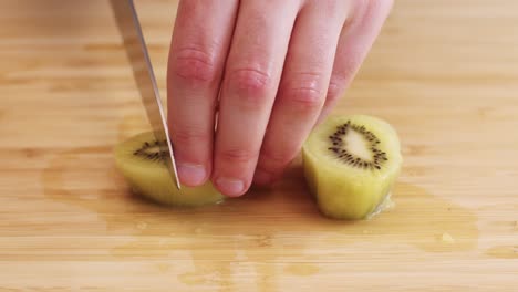 cerca de dos mitades de kiwi peladas siendo cortadas en trozos