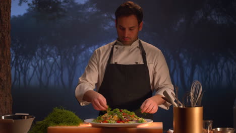 chef plating a fresh salad outdoors at dusk