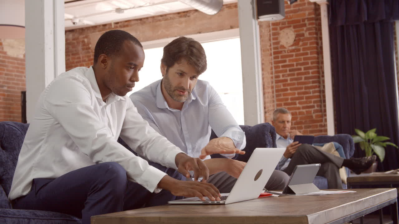 사무실 의 휴식 구역 에서 소파 에서 일 하는 사업가 들