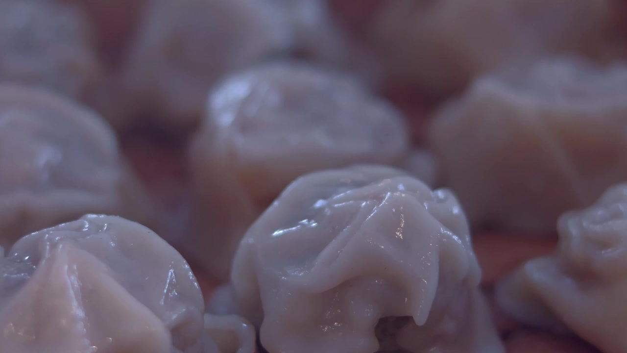 Close-up detail shot showing texture, details and steam emanating from Xiao long bao or steamed soup dumplings, part of traditional Cantonese dimsum style of dining