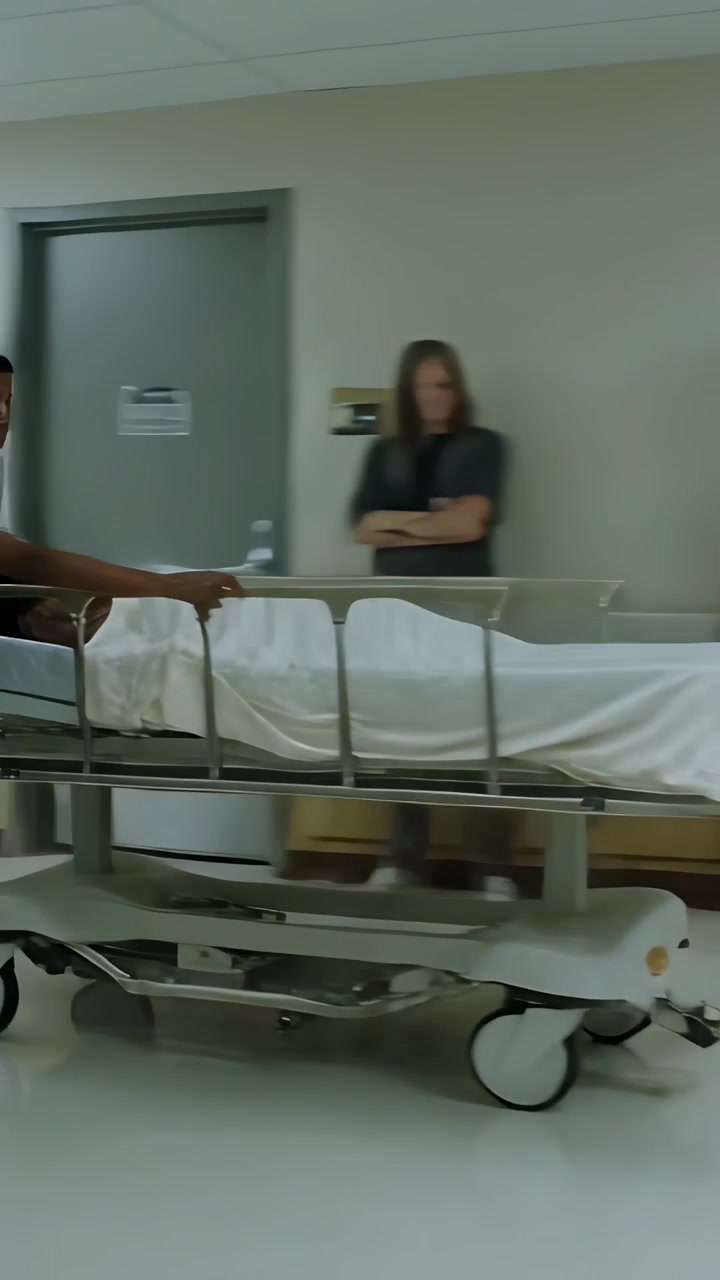 Vídeo vertical: Agarrando o corrimão, equipe hospitalar de uniforme empurrando maca com lençol branco em direção à cirurgia