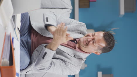 Vertical-video-of-Home-office-worker-old-man-applauding-what-he-sees-on-laptop.