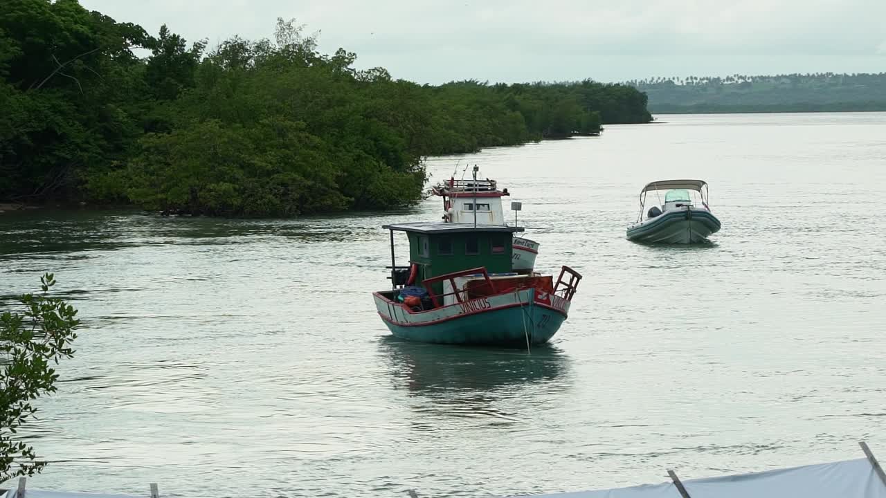 Slow motion shot of small fishing boats docked at the Tibau do Sul port on the large Guara&iacute;ras Lagoon in Rio Grande do Norte, Brazil on an overcast day