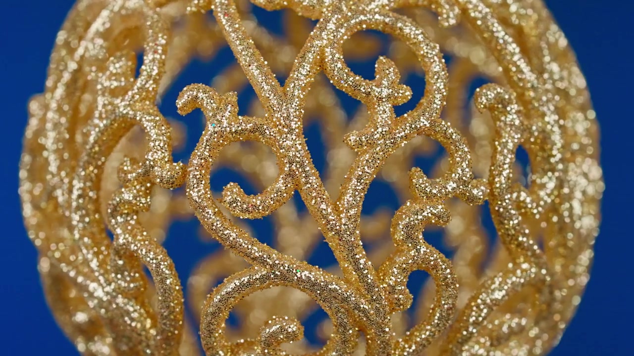 Decorazione natalizia con glitter dorati in rotazione su sfondo blu.