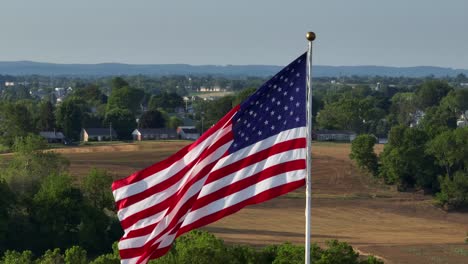 Große-Ikonische-Amerikanische-Flagge,-Malerische-Landschaft-Im-Hintergrund,-Luftorbit