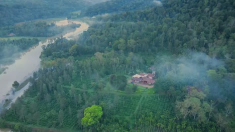 aerial flight between mystic fog with green trees and lonely villa surrounded by mangroves forest in india