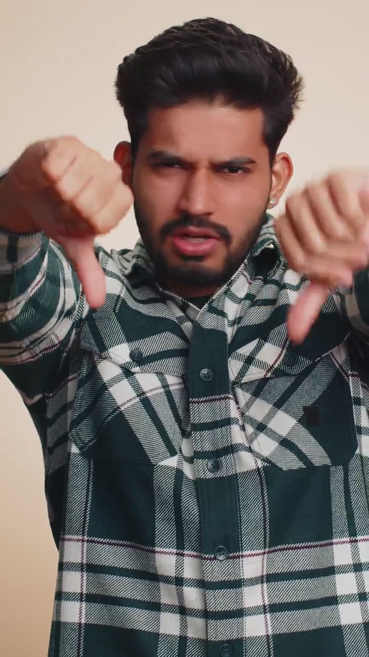 Upset handsome man boy in shirt showing thumbs down sign gesture disapproval dissatisfied dislike