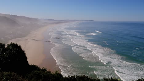 Vista-Desde-La-Montaña-Sobre-Un-Amplio-Tramo-De-Hermosa-Playa-Con-Olas-Rodando-Hacia-Ella