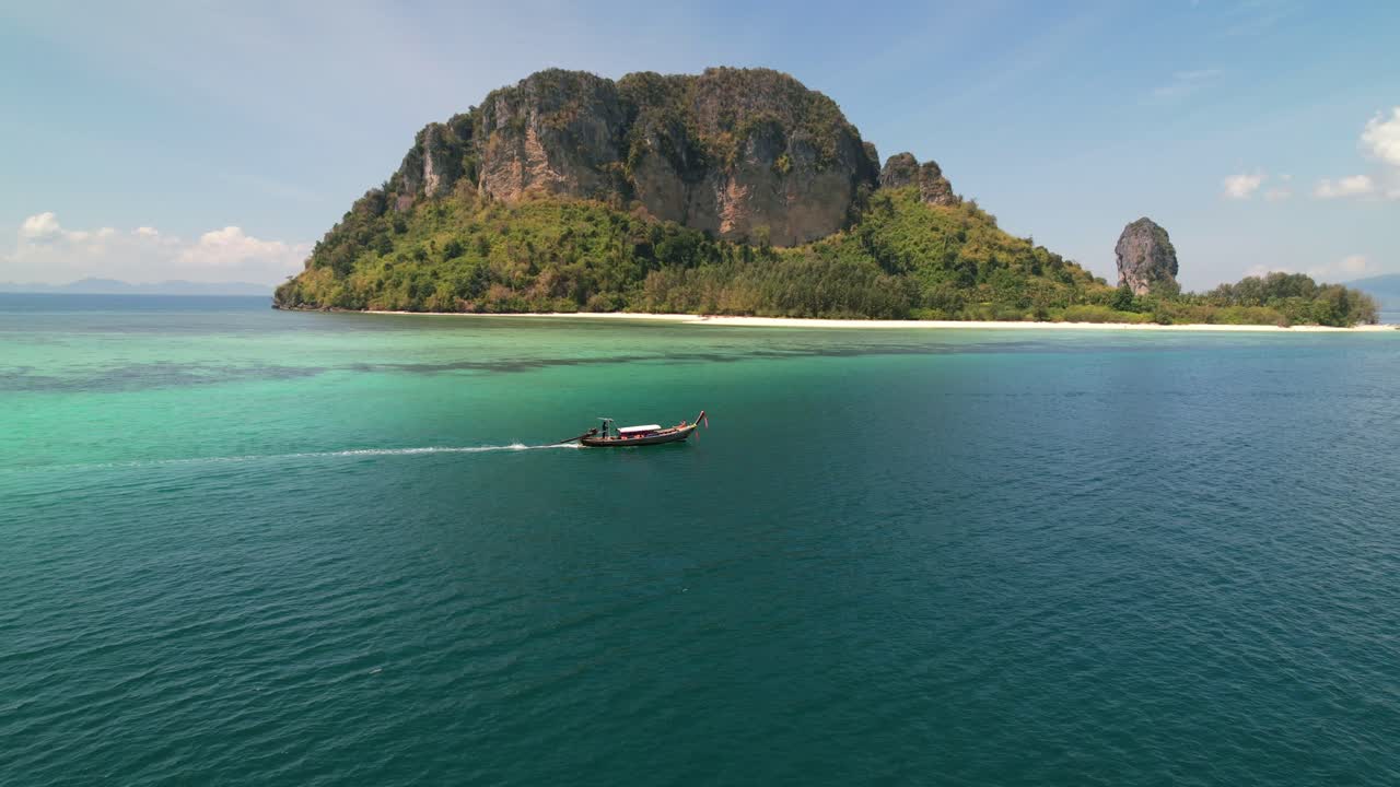 beautiful tropical panoramic landscape of a Thai longtail boat motoring past Ko Poda Island in the andaman sea of Krabi Thailand on a sunny morning with stunning turquoise green and blue water