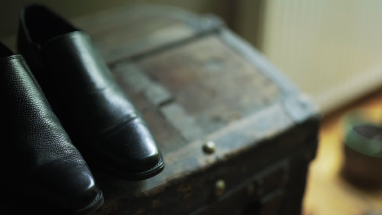 Eleganti scarpe in pelle nera che poggiano su una vecchia cassa di legno.